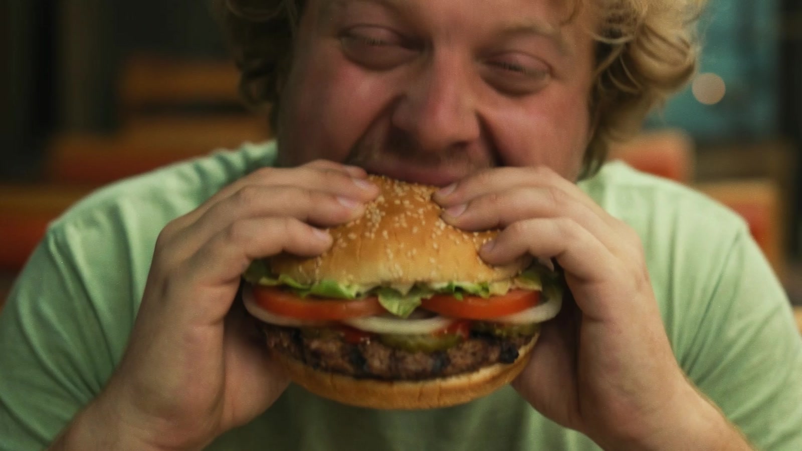 A man biting into a burger in extreme close-up