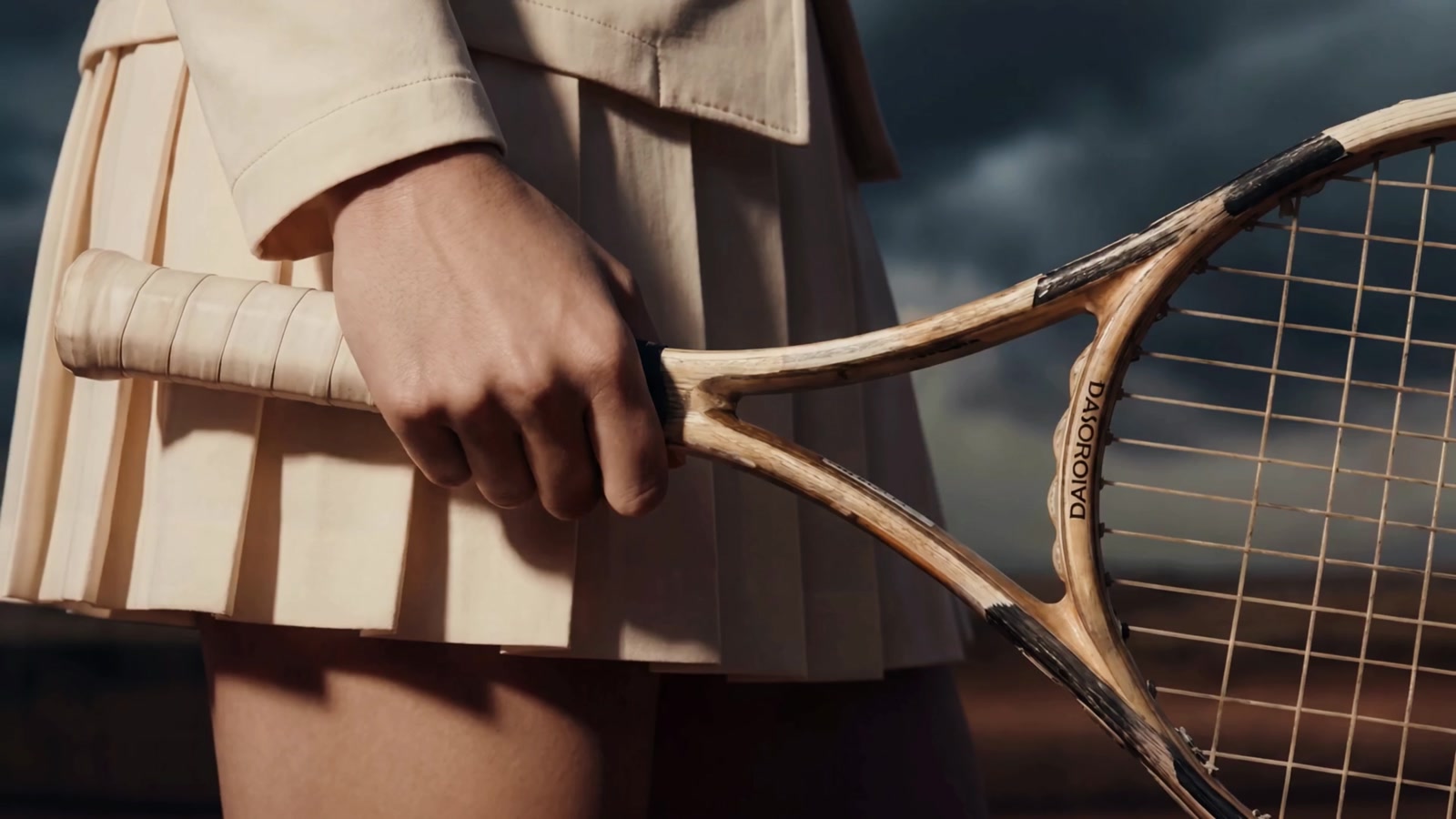 A tennis player with her racket, storm sky behind