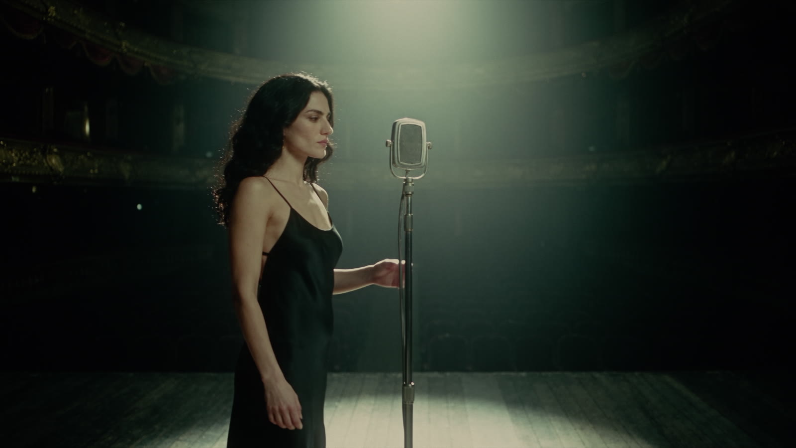 The singer at a vintage ribbon microphone in a black slip dress
