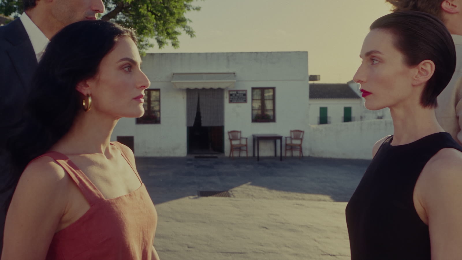 Two women facing each other in the square, one in red, one in black