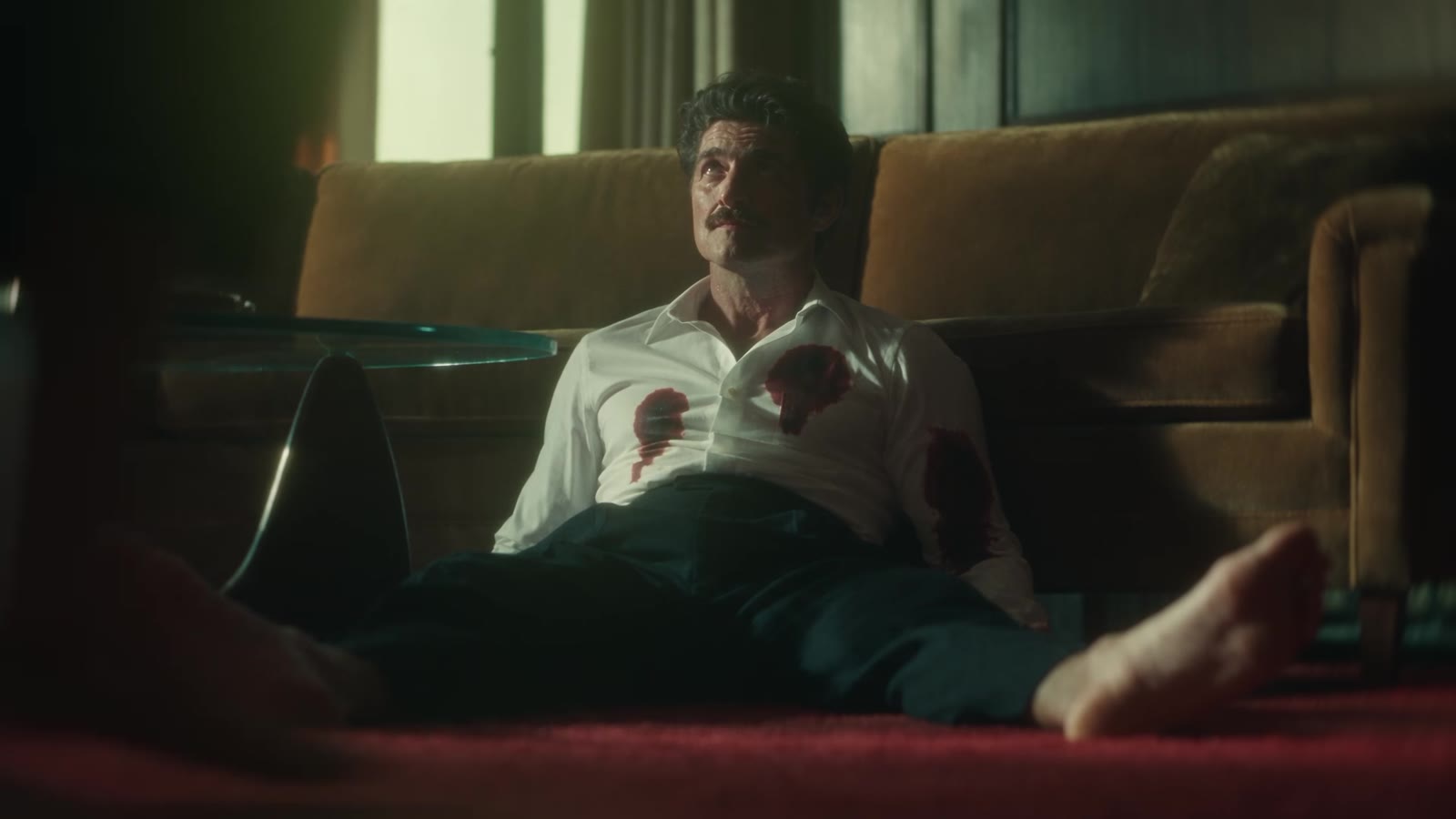 A man on the carpet, a stain spreading across his white shirt