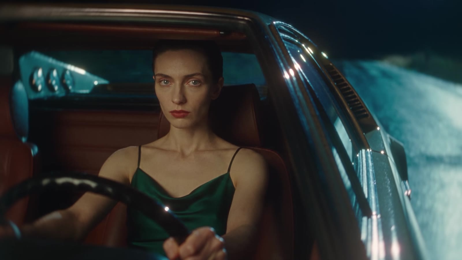 The woman at the wheel of a convertible at night